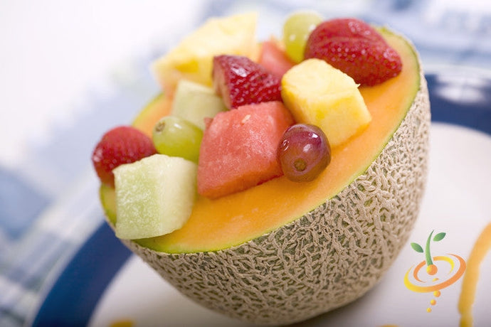 Honey Rock seeds cantaloupe melon half filled with mixed fruit salad including strawberries, grapes, pineapple, and watermelon chunks